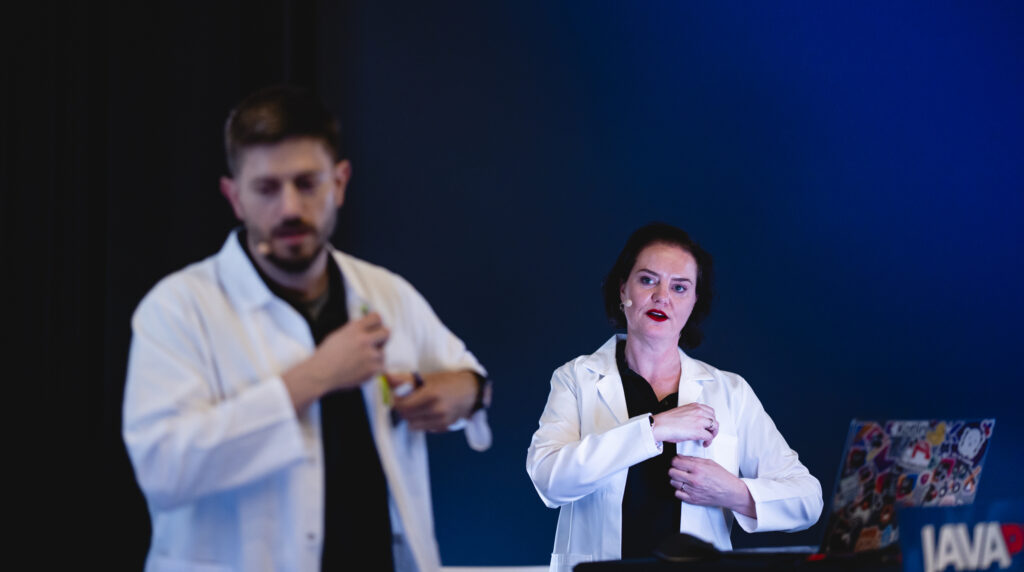 Piotr Przybył and Marit van Dijk simultaneously putting a pen in the front pocket of their labcoat.