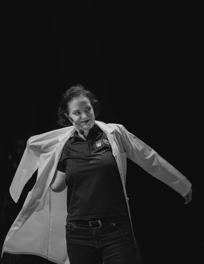 Black and white photo of Marit van Dijk putting on her labcoat over a Java Champion polo.