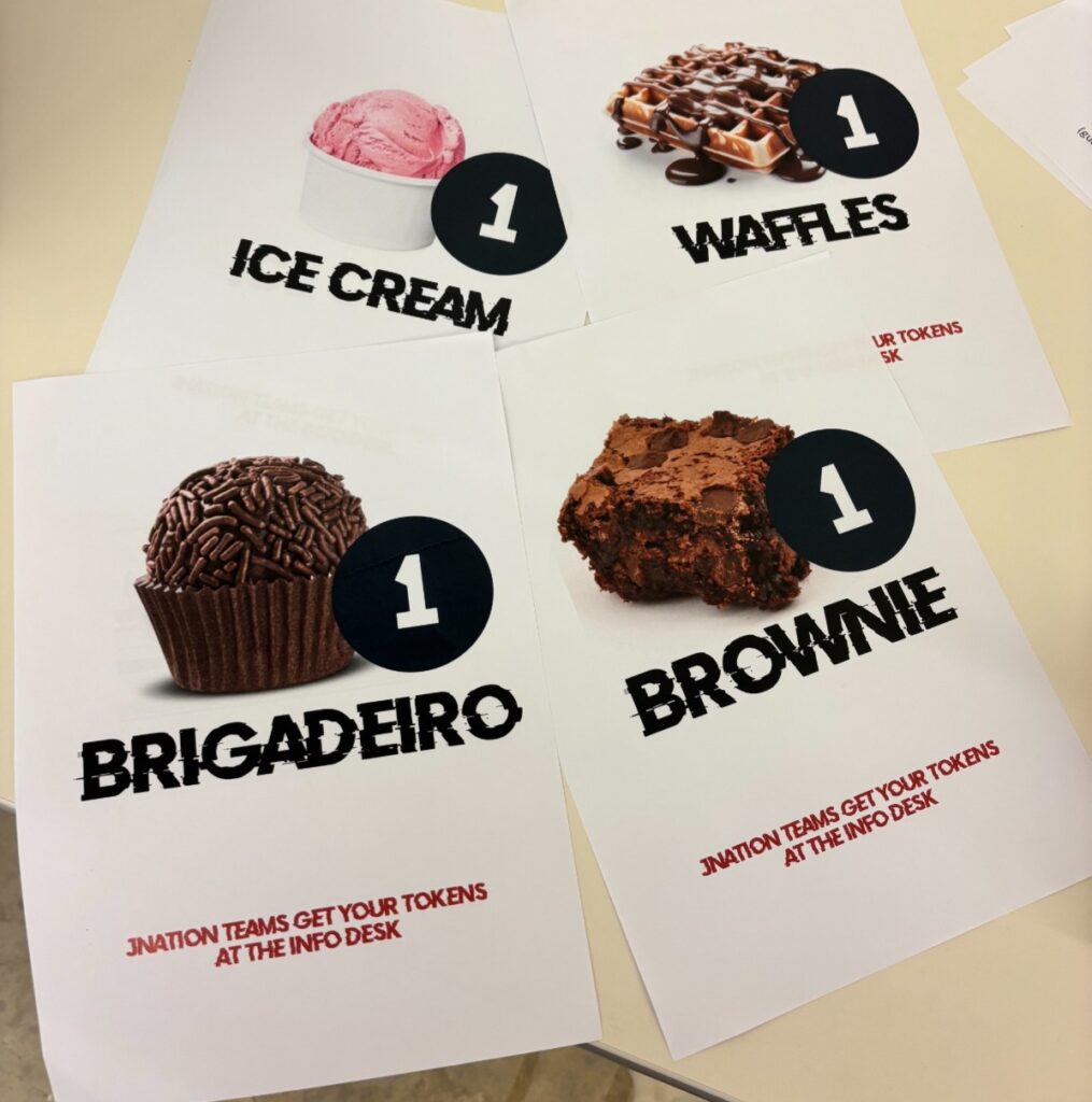 Flyers with pictures of ice cream, waffles, brigadeiro and brownie, and the text "JNation teams get tour tokens at the info desk".